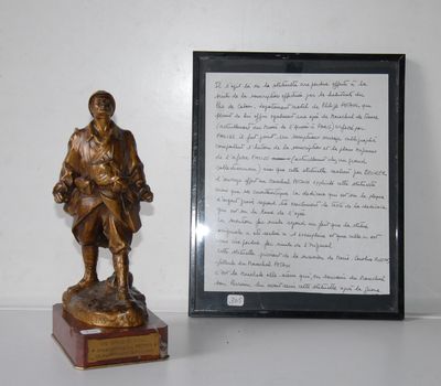 a bronze statue of a man holding a book next to a framed picture