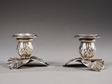 pair of silver candlesticks with leaves on each of them