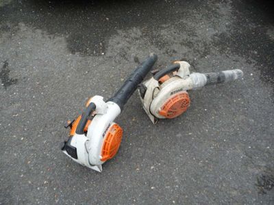 two chainsaws laying on the ground next to a car