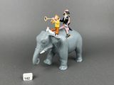 figurines of people riding on top of an elephant on a gray surface