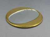 miroir rond plaqué or sur fond gris avec reflet