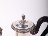 a silver tea pot sitting on a table with a black handle