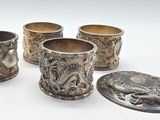 quatre coupes en argent ornées de motifs, posées sur une surface blanche