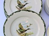 four plates with birds painted on them sitting on a table