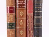 several old books are stacked on top of each other on a white surface