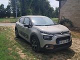 une voiture argentée garée devant un immeuble, sur un chemin de terre