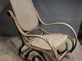 a rocking chair that has a wicker seat on it