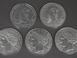 four silver coins of different sizes and shapes on a black surface
