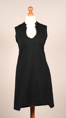 La robe est noire et présente un décolleté en V.