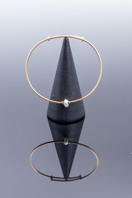un gros plan d'une bague posée sur un cône, sur une surface réfléchissante