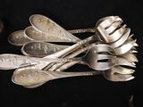 a lot of silver spoons and forks on a black table