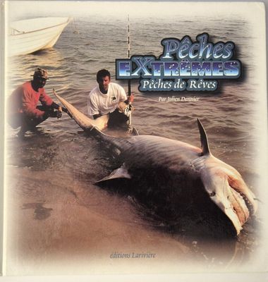 two men standing next to a dead shark in the water