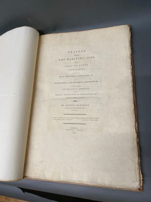 un livre ouvert posé sur une table, à côté d'une table en bois