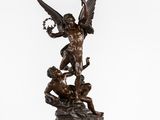 une statue en bronze représentant un ange et un homme, posée sur un socle