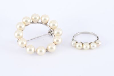 une paire de perles blanches et une bague en argent sur fond blanc