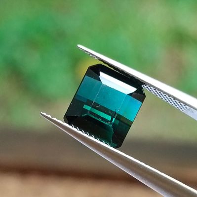 a close up of a piece of green stone being held by a pair of pliers