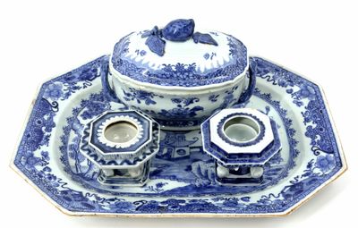 a blue and white plate with a bowl and a candle holder on it