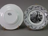 two plates with black and white designs on them sitting next to each other