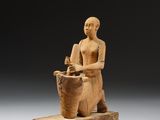 une image représentant la statue d'un homme assis sur un bloc de bois