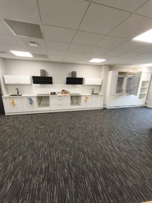 a room with a tv, cabinets, and a desk in it