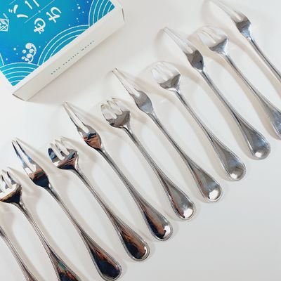 several forks and spoons are lined up next to a box of toothpaste