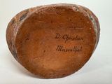 a brown vase with writing on it sitting on a white surface