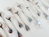 a lot of spoons and forks on a white table