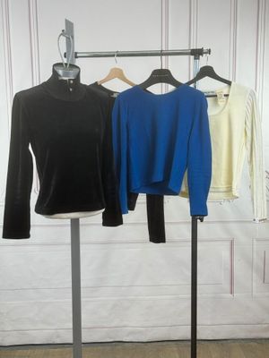three shirts are hanging on a clothes rack in front of a white wall