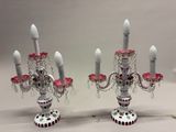 une paire de bougeoirs roses et blancs avec des lustres en cristal