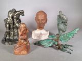 trois statues représentant des personnes et un oiseau posées sur une table