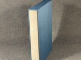 the blue book is sitting on a brown cloth covered surface