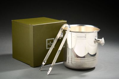 une tasse en argent contenant une cuillère, posée à côté d'une boîte verte