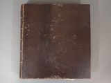 an old book with a brown cover on a white surface