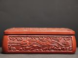 an old red carved box sitting on top of a table