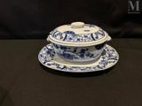 an image of a blue and white bowl and saucer on a black table