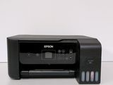 a black printer sitting on top of a table next to a white wall