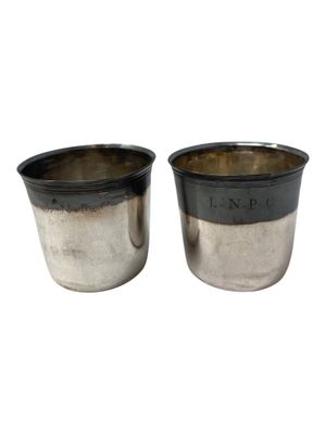 two silver cups with black rims are sitting side by side