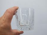 a hand holding a glass with a liquid inside of it