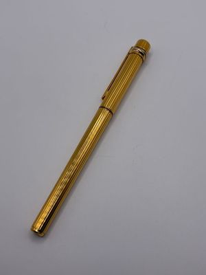 un stylo doré posé sur une table blanche