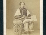 une vieille photo en noir et blanc d'une femme assise sur un tabouret