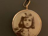 an old photo of a young girl in a dress is shown in a pendant