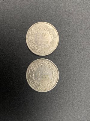 two silver coins sitting side by side on a black surface