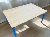 une table en bois aux pieds bleus dans une pièce