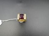 gros plan d'une bague en or avec une pierre rouge