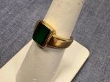 Gros plan sur une bague en or ornée d'une pierre verte