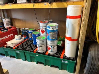 de nombreux pots de peinture posés sur une étagère dans un garage