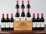 Des bouteilles de vin rouge sont alignées sur une table, à côté d'une caisse en bois