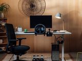 a desk with a computer, speakers, and a chair in a room