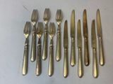 six fourchettes et un couteau sont disposés en rang sur une table