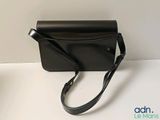 the small black purse is sitting on the table next to a plant